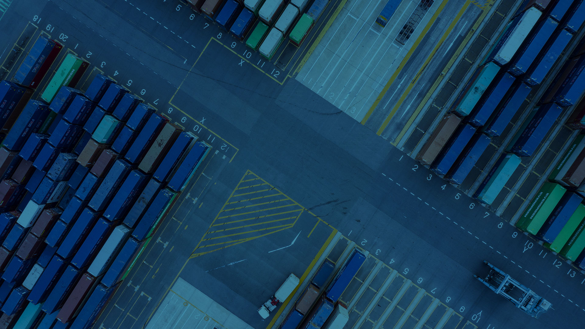 rotterdamse containerterminal gezien vanaf boven, containers staan in genummerde vakken langs een weg waar containerskranen rijden